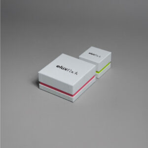 Two minimalistic white cardboard boxes with subtle colored accents, one with a red line and the other with a green line, perfect for perfume or jewelry packaging.